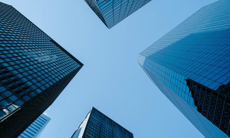 pexels-photo-7078666-7078666 Low angle of high business towers with glass mirrored windows located in megalopolis downtown against blue sky